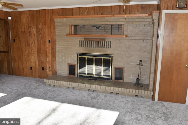 room details featuring wooden walls, carpet flooring, ceiling fan, ornamental molding, and a fireplace