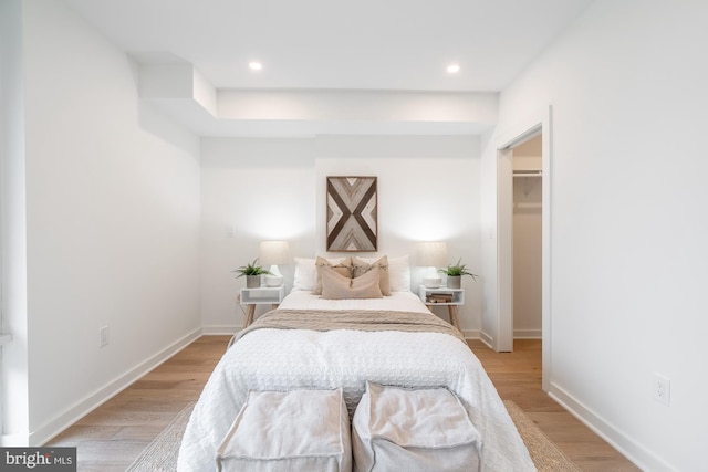 bedroom featuring a walk in closet, light hardwood / wood-style floors, and a closet