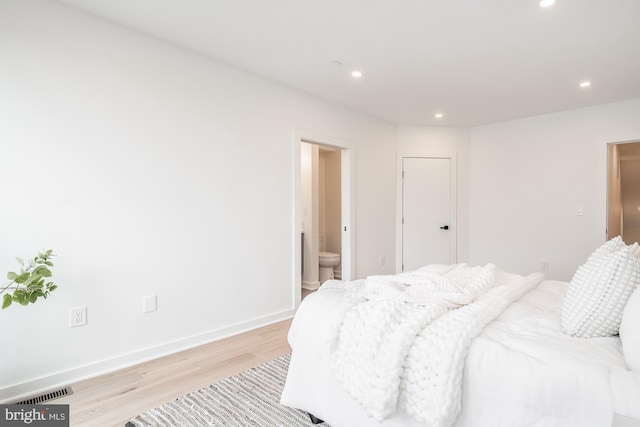 bedroom with light wood-type flooring and ensuite bath