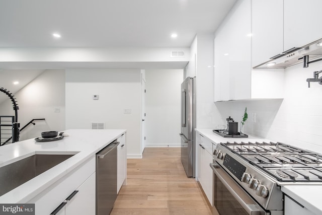 kitchen with sink, stainless steel appliances, light hardwood / wood-style floors, decorative backsplash, and white cabinets