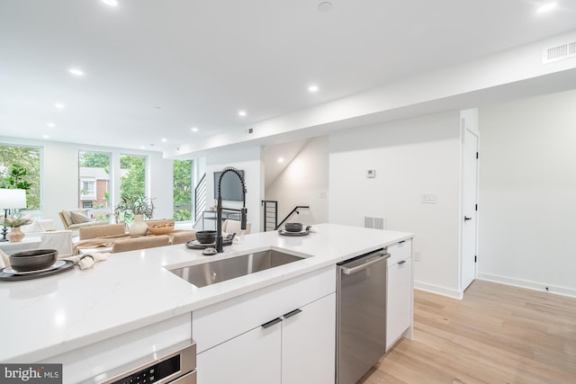 kitchen featuring light stone countertops, white cabinets, sink, dishwasher, and light hardwood / wood-style floors