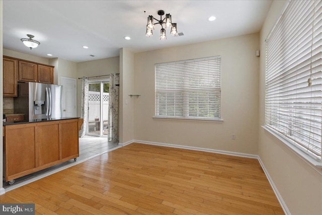 kitchen with a notable chandelier, stainless steel fridge, and light hardwood / wood-style floors