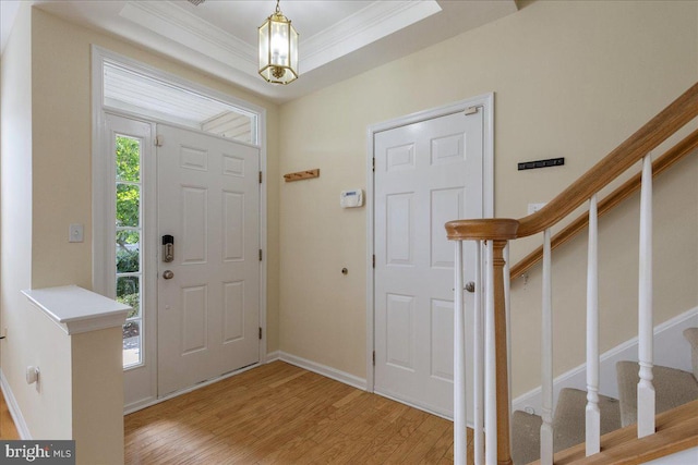 foyer entrance featuring a tray ceiling, light hardwood / wood-style flooring, and ornamental molding