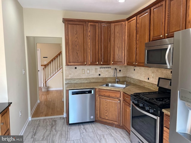 kitchen featuring sink, stainless steel appliances, light stone counters, light hardwood / wood-style flooring, and backsplash