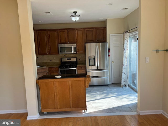 kitchen featuring tasteful backsplash, appliances with stainless steel finishes, and light hardwood / wood-style flooring