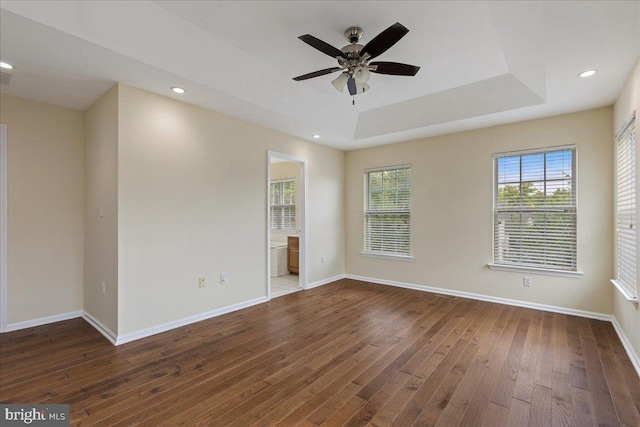 empty room featuring ceiling fan, dark hardwood / wood-style flooring, and a tray ceiling