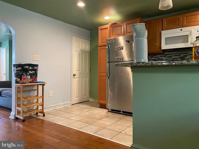 kitchen featuring backsplash, stainless steel fridge, and light wood-type flooring