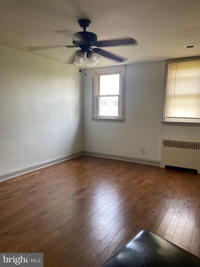 unfurnished room featuring ceiling fan, radiator heating unit, and dark wood-type flooring