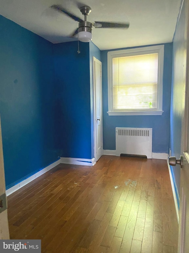 spare room featuring radiator heating unit, ceiling fan, and hardwood / wood-style floors