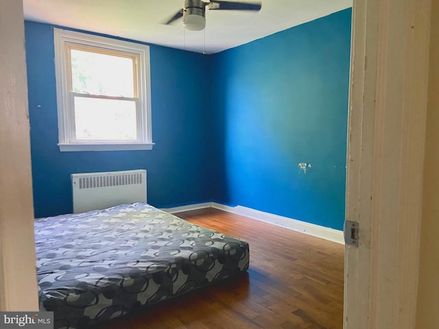 bedroom featuring radiator heating unit, ceiling fan, and hardwood / wood-style floors