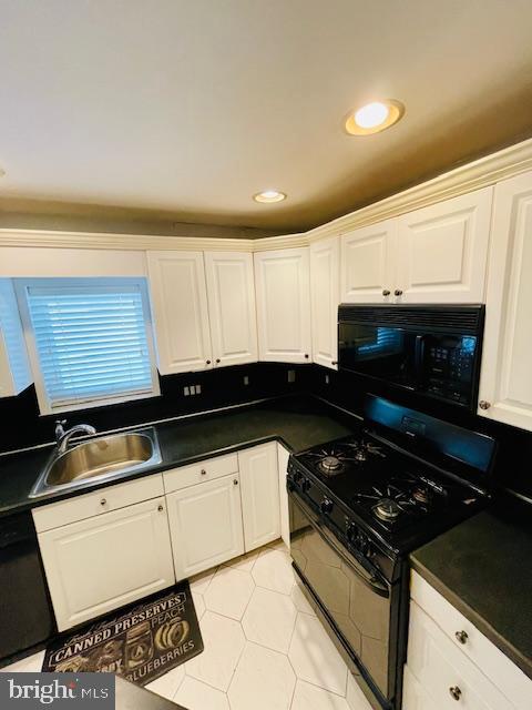 kitchen with white cabinets, light tile patterned floors, sink, and black appliances