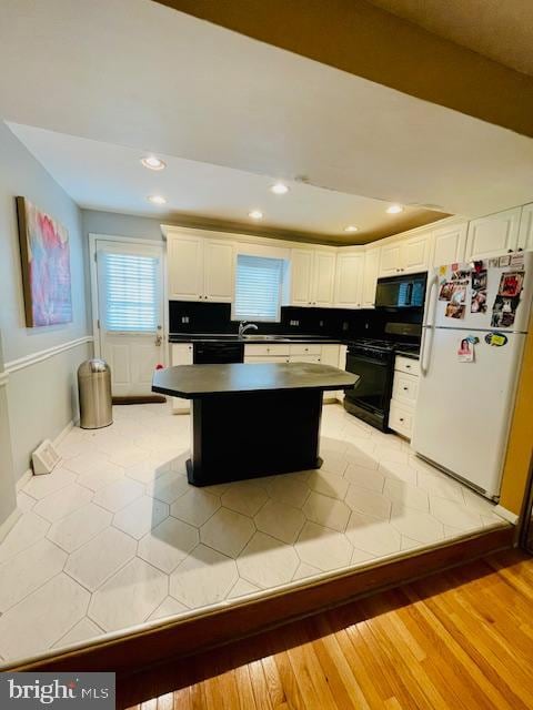 kitchen with black appliances, light hardwood / wood-style floors, white cabinetry, and backsplash