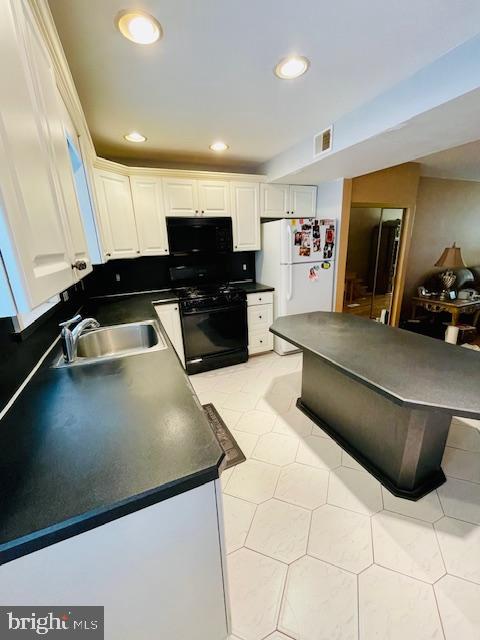 kitchen with black appliances, light tile patterned flooring, white cabinets, and sink