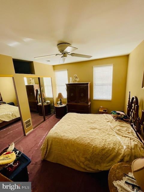 carpeted bedroom featuring multiple windows and ceiling fan