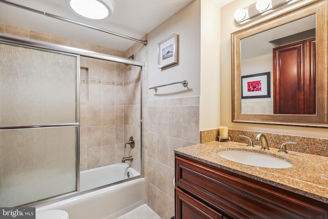 full bathroom featuring vanity, enclosed tub / shower combo, tile walls, and toilet