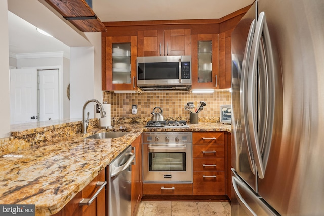 kitchen featuring light stone counters, sink, stainless steel appliances, and ornamental molding