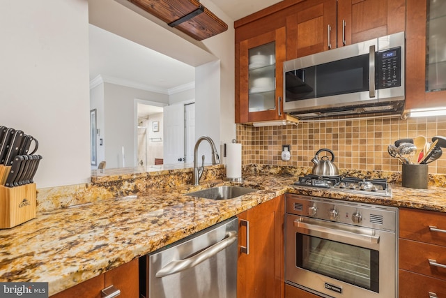 kitchen featuring sink, ornamental molding, tasteful backsplash, light stone counters, and stainless steel appliances