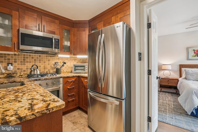 1239 Vermont Ave NW Unit 602, Washington, DC 20005 - kitchen featuring stainless steel appliances, a sink, brown cabinets, tasteful backsplash, and light stone counters