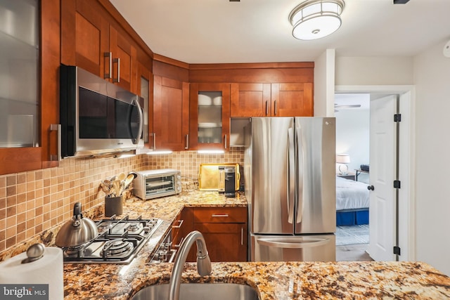 kitchen featuring sink, decorative backsplash, light stone counters, and stainless steel appliances