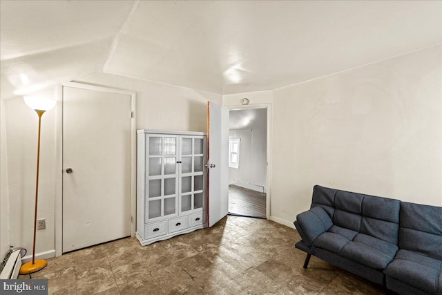 living area featuring vaulted ceiling and a baseboard heating unit