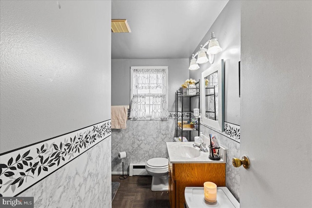 bathroom with vanity, toilet, tile walls, and a baseboard heating unit