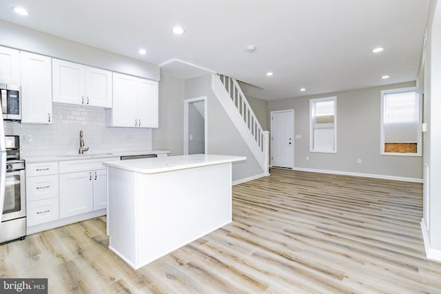 kitchen featuring white cabinets, a center island, light wood-type flooring, and sink