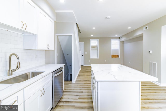 kitchen featuring dishwasher, white cabinets, sink, light wood-type flooring, and a kitchen island