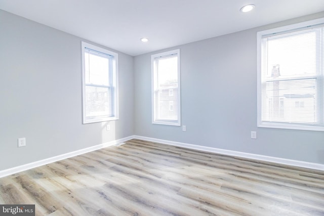 empty room with a healthy amount of sunlight and light hardwood / wood-style floors