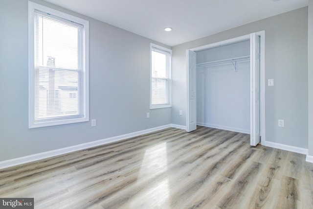 unfurnished bedroom with light hardwood / wood-style flooring and a closet