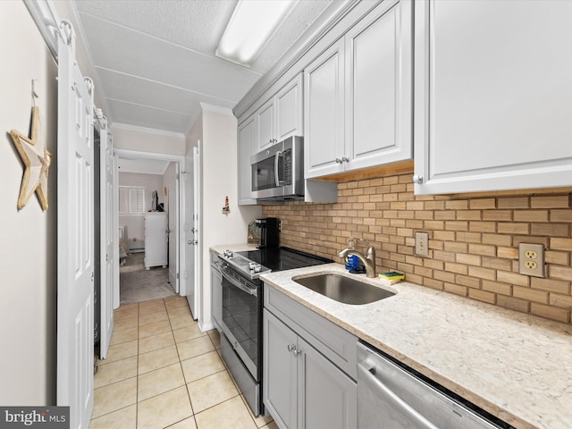 kitchen with backsplash, crown molding, sink, light tile patterned flooring, and stainless steel appliances