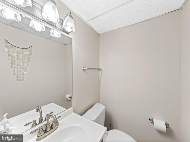 bathroom featuring sink, a drop ceiling, and toilet