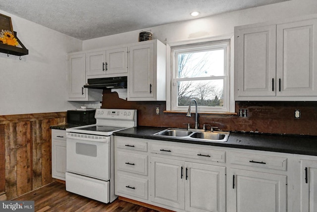 kitchen with wood walls, white cabinets, electric stove, sink, and a textured ceiling