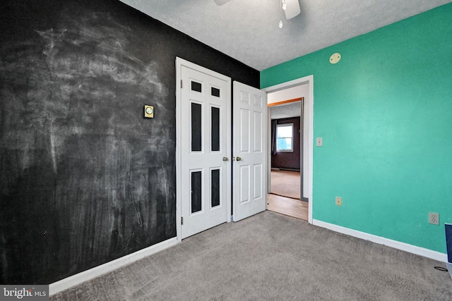 unfurnished bedroom featuring carpet, ceiling fan, and a textured ceiling