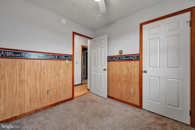 unfurnished bedroom with a textured ceiling, light colored carpet, and ceiling fan