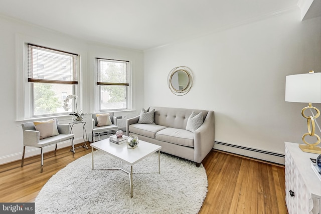 living room with wood-type flooring, crown molding, and a baseboard heating unit