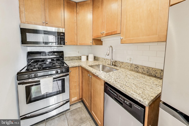 kitchen featuring light stone countertops, appliances with stainless steel finishes, decorative backsplash, sink, and light tile patterned flooring