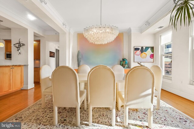 dining room featuring a chandelier, light hardwood / wood-style floors, and ornamental molding