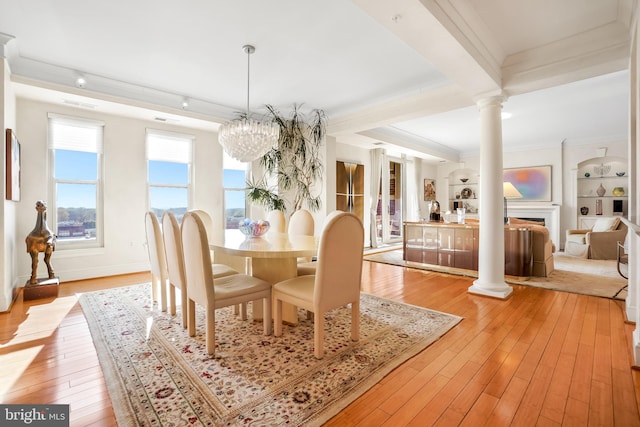 dining room with ornate columns, crown molding, built in features, a chandelier, and light hardwood / wood-style floors