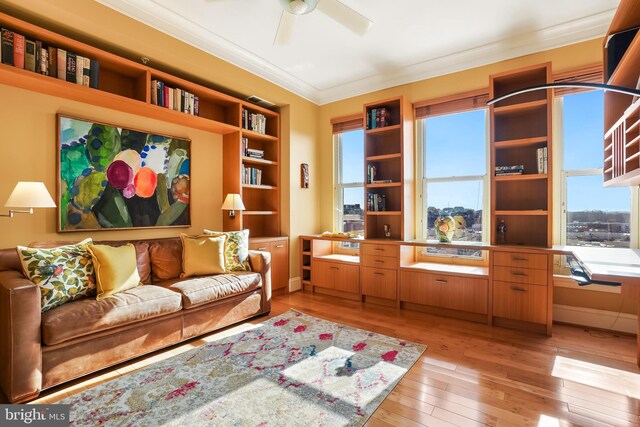 living room featuring ceiling fan, light wood-type flooring, and crown molding