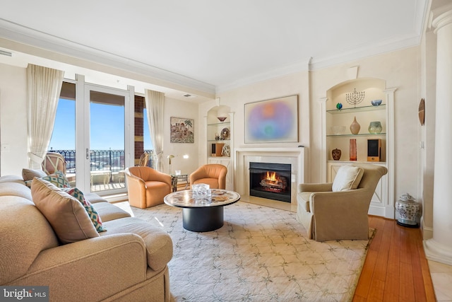 living room with crown molding, built in features, and light hardwood / wood-style floors