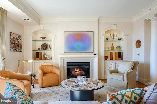 living room featuring built in shelves, crown molding, and light wood-type flooring