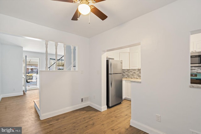 kitchen featuring white cabinets, decorative backsplash, ceiling fan, light hardwood / wood-style floors, and stainless steel appliances