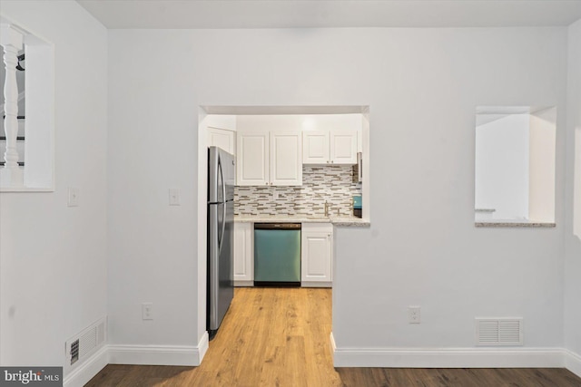 kitchen with decorative backsplash, appliances with stainless steel finishes, light hardwood / wood-style flooring, and white cabinetry