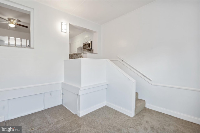 stairs with carpet floors and ceiling fan