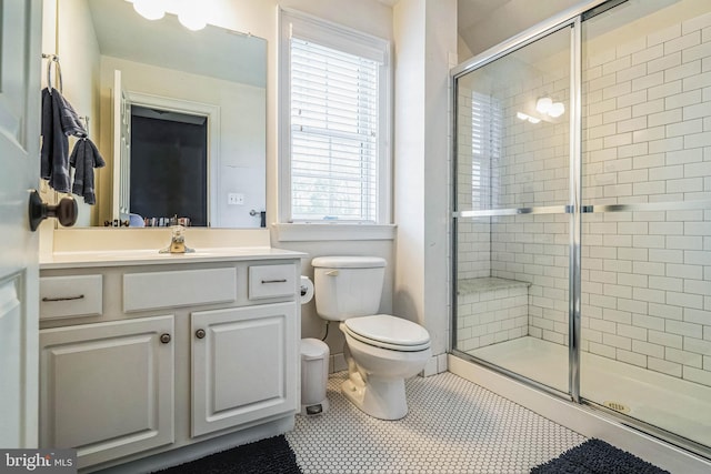 bathroom with tile patterned floors, vanity, toilet, and a shower with door