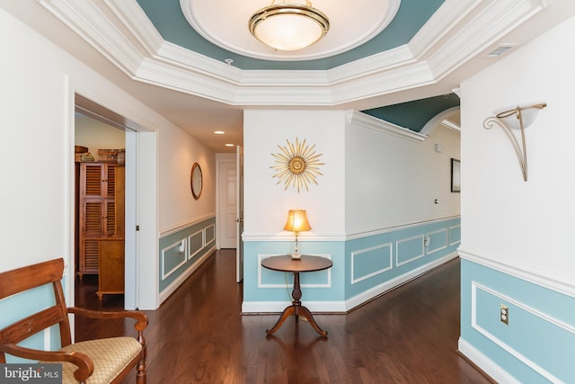 hall with dark hardwood / wood-style floors, a raised ceiling, and crown molding