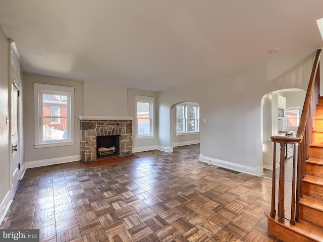 unfurnished living room with dark parquet floors and a fireplace