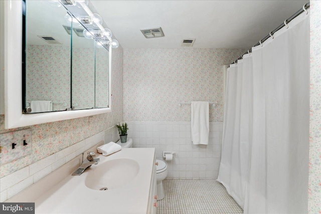 bathroom featuring toilet, vanity, tile patterned floors, and tile walls