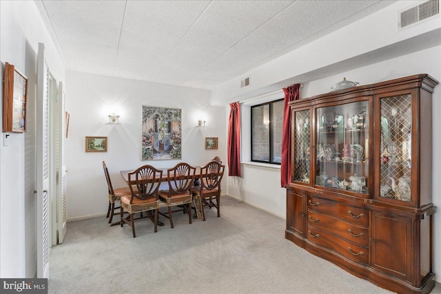 carpeted dining room with a textured ceiling