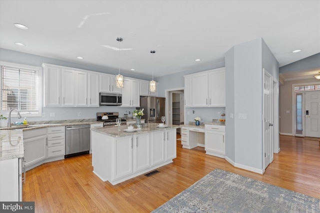 kitchen featuring a sink, stainless steel appliances, light wood-style flooring, and white cabinetry